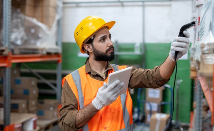 serious-young-bearded-man-hardhat-gloves-scanning-code-item-while-doing-stock-inventory-storeroom (1)